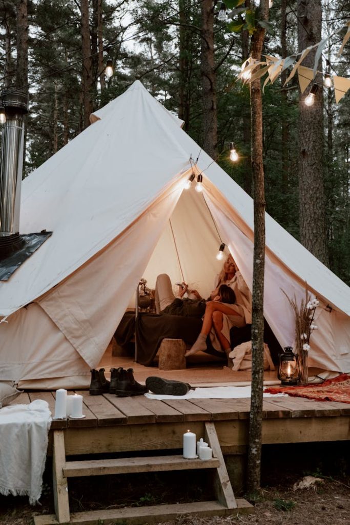 A romantic and cozy glamping scene in a luxurious forest tent with warm lighting.